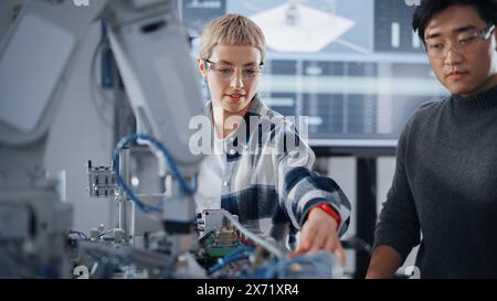 Neugierige Schüler tauschen Ideen untereinander aus, während sie gemeinsam an der Modifikation der Funktionen des mechanischen Arms für das Engineering-Projekt in der Schule in Workshop arbeiten. Informatikausbildung Stockfoto