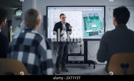 Vielfältiges Team von Studenten im Computerdesign, die sich an der Universität mit dem Lehrer unterhalten und interaktives Fernsehen ansehen, das ein 3D-Konzeptmodell der Leiterplatte zeigt. Bildungskonzept Stockfoto