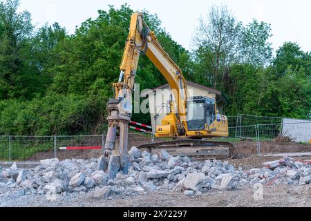 Gelber Bagger mit Betonpulverisierer am Baggerarm. Stockfoto