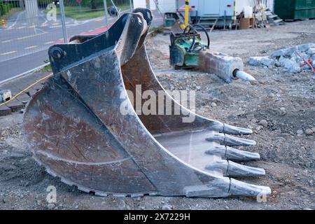 Großer Baggerlöffel auf dem Boden einer Baustelle. Sichtbare Markierungen verwenden. Im Hintergrund ein Betonmeißel. Stockfoto