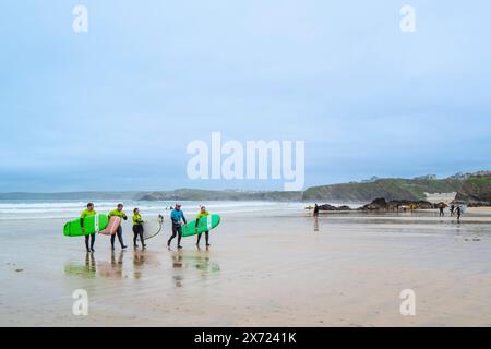 Ein Surflehrer der Escape Surf School geht mit einer Gruppe von Surfern am Towan Beach in Newquay in Cornwall, Großbritannien. Stockfoto