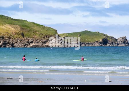 Urlauber, die im Meer am Towan Beach surfen, mit Towan Headland im Hintergrund an der zerklüfteten Küste von Newquay in Cornwall in Großbritannien. Stockfoto