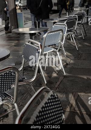 Frankreich, Paris - 03. Januar 2024 - Stühle und Tische aus Edelstahl vor einem Café auf der Straße in Paris. Leerer Sitzbereich im Freien mit Metallkaffee Stockfoto