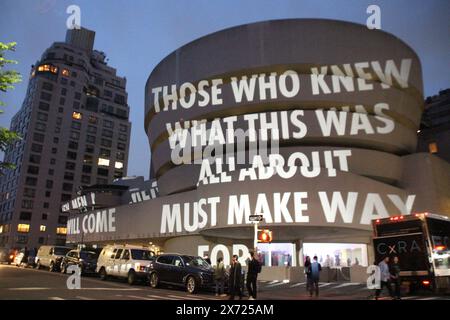 New York, USA. Mai 2024. Besucher stehen vor der Installation „for the Guggenheim“ der Künstlerin Jenny Holzer, die auf die Außenfassade des New Yorker Guggenheim Museums projiziert wird. Quelle: Christina Horsten/dpa/Alamy Live News Stockfoto