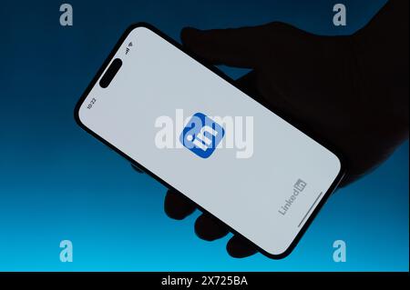 New York, USA – 6. Mai 2024: Öffnen Sie die Linkedin App auf dem Smartphone in Hand isolierter blauer Farbverlauf Stockfoto