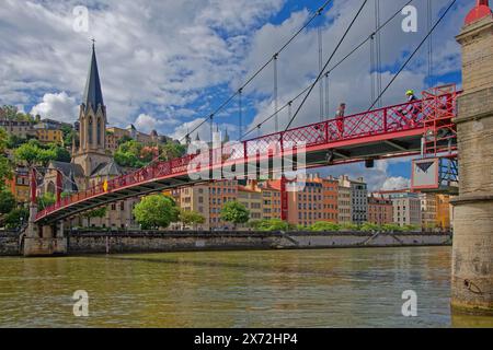 LYON, FRANKREICH, 15. Mai 2024: Radfahrer auf der Fußgängerbrücke über den Fluss Saone und die Kirche Saint-George im Stadtzentrum von Lyon. Stockfoto