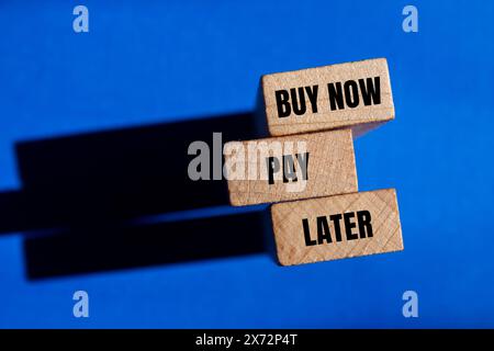 Kaufen Sie jetzt bezahlen Sie später Wörter auf Holzblöcken mit blauem Hintergrund. Symbol für „jetzt kaufen“, „später bezahlen“. Kopierbereich. Stockfoto