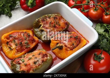 Leckere gefüllte Paprika in Schüssel und Zutaten auf dem Tisch, Nahaufnahme Stockfoto