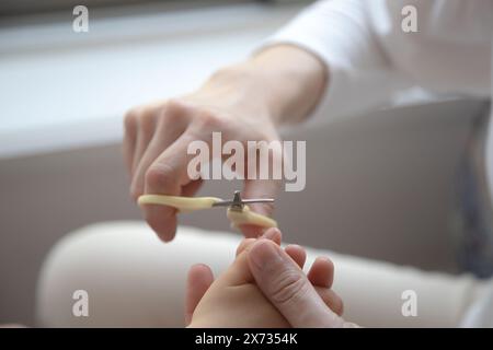 Nahaufnahme eines Erwachsenen, der die Fingernägel eines Kindes sorgfältig trimmt, um einen zarten Moment der Pflege und Pflege hervorzuheben. Stockfoto