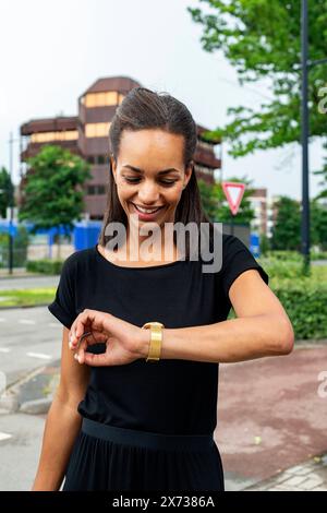 Histoire's Fashion Portrait junge Erwachsene, weibliche Modedesignerin, die ihre eigenen Kreationen trägt und ihre Armbanduhr und Uhr überprüft. Tilburg, Niederlande Stockfoto