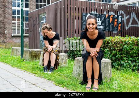 Histoire's Fashion zwei weibliche Modedesignerinnen sitzen auf einem Betonwürfel in einer ehemaligen Industrieanlage. Tilburg, Niederlande. MRYES Tilburg Stockfoto