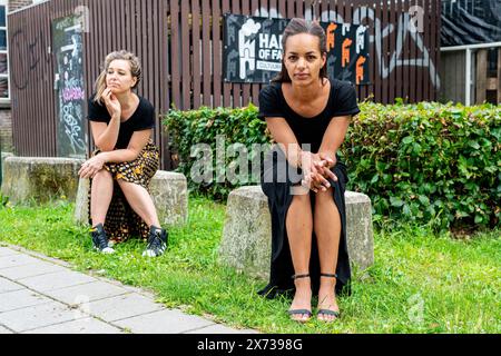 Histoire's Fashion zwei weibliche Modedesignerinnen sitzen auf einem Betonwürfel in einer ehemaligen Industrieanlage. Tilburg, Niederlande. MRYES Tilburg Stockfoto