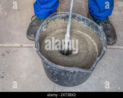 Bauarbeiter mischt Mörtel in einem Eimer mit handgeführtem Betonmischer Stockfoto