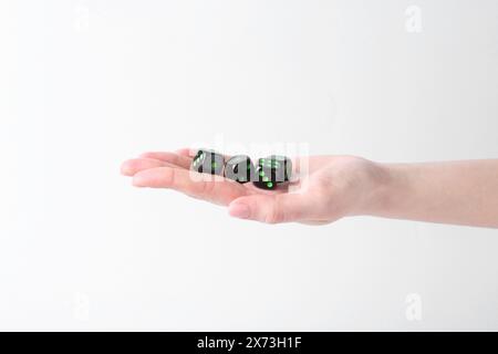 Frau, die Spielwürfel in der Hand auf weißem Hintergrund hält, Nahaufnahme Stockfoto