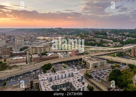 Blick von oben auf die Verkehrsinfrastruktur der USA. Luftaufnahme der amerikanischen Autobahnkreuzung bei Sonnenuntergang mit schnell fahrenden Fahrzeugen in Cincinnati Stockfoto