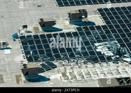 Draufsicht der durch den Hurrikan Ian zerstörten Photovoltaik-Solarpaneele, die auf dem Dach des Industriebaues zur Erzeugung von ökologischem Strom montiert sind Stockfoto