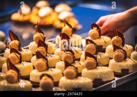 Die Hand einer Bäckerei-Verkäuferin legt glasierte Torten auf die Verkaufstheke. Vorbereitung am frühen Morgen für den Verkauf. Stockfoto