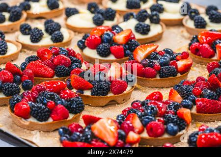 Tartlets mit Himbeeren, Brombeeren, Erdbeeren, Johannisbeeren, Heidelbeeren auf einem Tablett, vorbereitete im Hintergrund Stockfoto