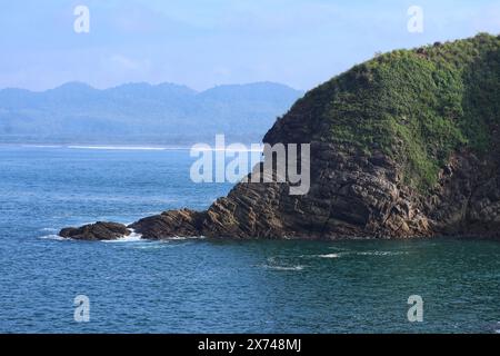 Felsen am Rande einer Koralleninsel mit ruhigen Meereswellen Stockfoto