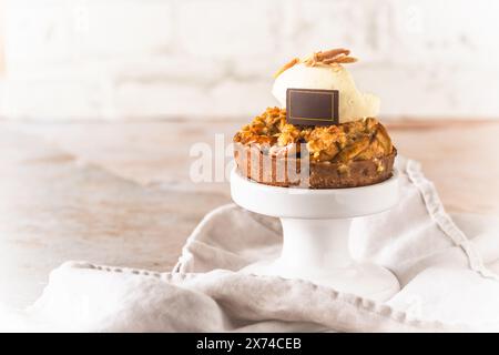 Tartlet aus knusprigem Teig mit Apfel und Streuseln und einem Topping weißer Creme auf einem weißen Kuchenständer, Kopierraum Stockfoto
