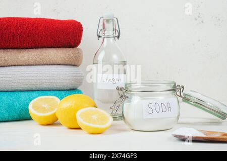 Backpulver im Glas, Essig, geschnittene Zitrone, gefaltetes Handtuch auf weißem Hintergrund. Das Konzept der organischen Entfärbung auf Kleidung Stockfoto