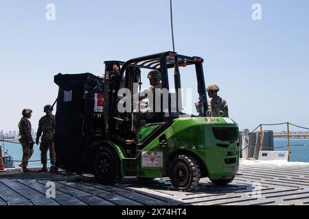 14. Mai 2024 - Ashdod, Israel - Soldaten der US-Armee, die der 7. Transportbrigade (Expeditionary) zugewiesen sind, transportieren mit einem Gabelstapler Paletten humanitärer Hilfe an Bord der MV Roy P. Benavidez im Hafen von Ashdod, Israel, 14. Mai 2024. Diese Soldaten unterstützen den Bau des Joint Logistics Over-the-Shore-Systems vor der Küste des Gazastreifens. Auf Ersuchen der Agentur der Vereinigten Staaten für internationale Entwicklung wird der vorübergehende Pier, die sogenannte Joint Logistics Over-the-Shore Capability, der humanitären Gemeinschaft bei der Bereitstellung internationaler humanitärer Hilfe für die Bürger helfen Stockfoto