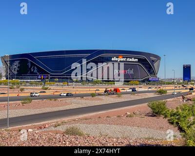 Las Vegas, NV, USA - 12. Mai 2024: Schwarzes Allegiant Stadium hinter der interstate 15 mit starkem Schild unter blauem Himmel. Leerer Parkplatz, Autos auf der Straße und gr Stockfoto