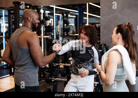 Gruppe sportlicher junger Menschen im Fitnessstudio, die sich beim gemeinsamen Training die Hände schütteln Stockfoto