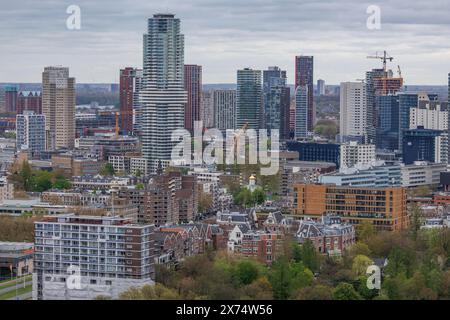 Moderne Hochhäuser und Wolkenkratzer prägen die Skyline der Stadt, umgeben von grünen Bäumen unter bewölktem Himmel, modernen Häusern und einer Brücke Stockfoto