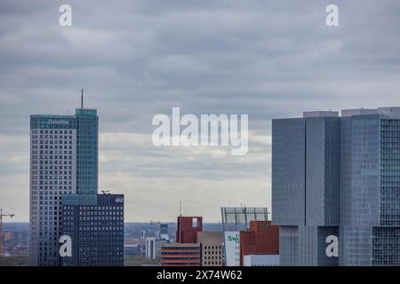 Graue Wolkenkratzer dominieren die Skyline der Stadt, unter einem ebenso grauen wie bewölkten Himmel, modernen Häusern und einer Brücke mit einem Fluss von oben, Rotterdam Stockfoto
