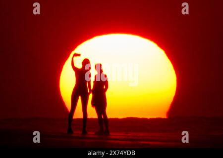 Isle Of Palms, Usa. Mai 2024. Die Menschen, die von Sonnenaufgang umgeben sind, machen ein Selfie am Strand, während das rekordverdächtige heiße Wetter am 17. Mai 2024 in Isle of Palms, South Carolina, über die Südostküste fegte. Quelle: Richard Ellis/Richard Ellis/Alamy Live News Stockfoto