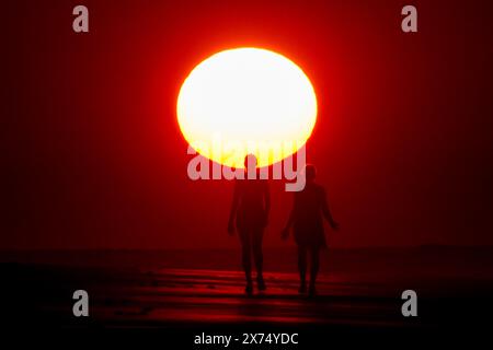 Isle Of Palms, Usa. Mai 2024. Die Menschen, die vom Sonnenaufgang umgeben sind, machen einen Spaziergang am Strand, während das heisse Wetter am 17. Mai 2024 in Isle of Palms, South Carolina, über die Südostküste fegte. Quelle: Richard Ellis/Richard Ellis/Alamy Live News Stockfoto