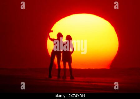 Isle Of Palms, Usa. Mai 2024. Die Menschen, die von Sonnenaufgang umgeben sind, machen ein Selfie am Strand, während das rekordverdächtige heiße Wetter am 17. Mai 2024 in Isle of Palms, South Carolina, über die Südostküste fegte. Quelle: Richard Ellis/Richard Ellis/Alamy Live News Stockfoto