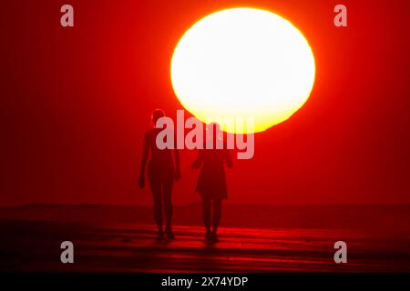 Isle Of Palms, Usa. Mai 2024. Die Menschen, die vom Sonnenaufgang umgeben sind, machen einen Spaziergang am Strand, während das heisse Wetter am 17. Mai 2024 in Isle of Palms, South Carolina, über die Südostküste fegte. Quelle: Richard Ellis/Richard Ellis/Alamy Live News Stockfoto