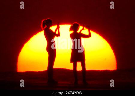 Isle Of Palms, Usa. Mai 2024. Die Menschen, die von Sonnenaufgang umgeben sind, machen ein Selfie am Strand, während das rekordverdächtige heiße Wetter am 17. Mai 2024 in Isle of Palms, South Carolina, über die Südostküste fegte. Quelle: Richard Ellis/Richard Ellis/Alamy Live News Stockfoto