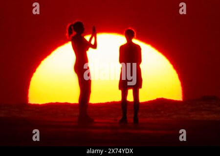 Isle Of Palms, Usa. Mai 2024. Die Menschen, die von Sonnenaufgang umgeben sind, machen ein Selfie am Strand, während das rekordverdächtige heiße Wetter am 17. Mai 2024 in Isle of Palms, South Carolina, über die Südostküste fegte. Quelle: Richard Ellis/Richard Ellis/Alamy Live News Stockfoto