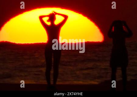 Isle Of Palms, Usa. Mai 2024. Die Menschen, die von Sonnenaufgang umgeben sind, machen ein Selfie am Strand, während das rekordverdächtige heiße Wetter am 17. Mai 2024 in Isle of Palms, South Carolina, über die Südostküste fegte. Quelle: Richard Ellis/Richard Ellis/Alamy Live News Stockfoto