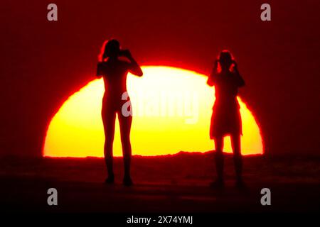 Isle Of Palms, Usa. Mai 2024. Die Menschen, die von Sonnenaufgang umgeben sind, machen ein Selfie am Strand, während das rekordverdächtige heiße Wetter am 17. Mai 2024 in Isle of Palms, South Carolina, über die Südostküste fegte. Quelle: Richard Ellis/Richard Ellis/Alamy Live News Stockfoto