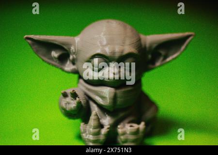 Madrid, Spanien 7. Mai 2024 DIN Grogu, Star Wars Spielzeugheld aus recyceltem Kunststoff isoliert auf grünem Hintergrund. Happy Baby Yoda aus der Disney-Serie. Stockfoto