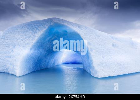 Eine große blaue Eisberghöhle mit einer kleinen Öffnung in der Mitte, die auf dem Argentinien-See schwimmt. Stockfoto