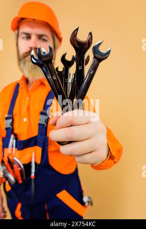 Wartung und Service der Fahrzeugpflege. Techniker, Automechaniker mit vielen Schraubenschlüsseln. Industriearbeiter, Handwerker in Schutzhelm und Overall. Stockfoto