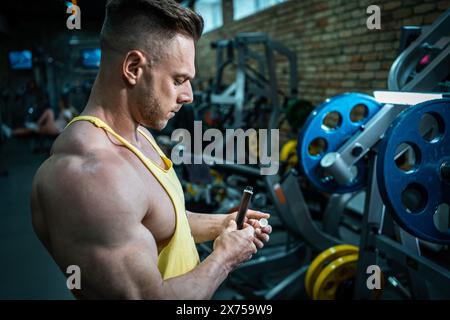 Muskelathlet trinken flüssiges Vitamin b 12 oder Ergänzung in kleiner Einweg-schwarzer Flasche, Bodybuilder-Mann mit Sporternährung in Ampule-Tropfen Stockfoto