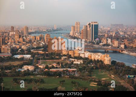 Aus der Vogelperspektive von Kairo mit dem Nil, modernen Türmen, Brücken und dichten Gebäuden, die sich über die Stadt erstrecken, mit grünen Parks im Vordergrund darunter. Stockfoto