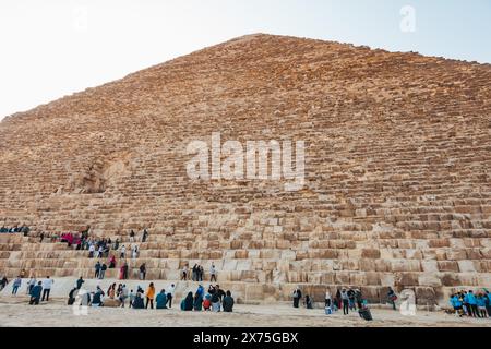Touristen treffen sich am Fuße der Großen Pyramide von Gizeh, Ägypten, und klettern ihre massiven Steinstufen unter der Sonne Stockfoto