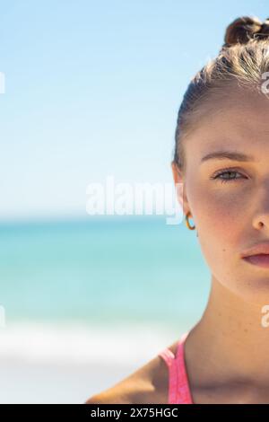 Am Strand steht eine kaukasische junge Frau, die nach vorne blickt, in rosa Oberteil, Kopierraum Stockfoto