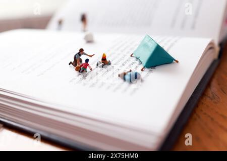 Miniaturmenschen, die Einen Lagerstopp haben und Feuer auf Ein Buch abbrennen. Stockfoto