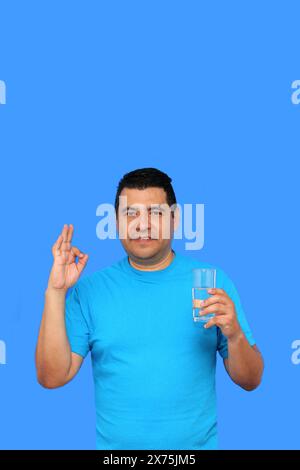 Dunkelhäutiger erwachsener Latino-Mann zeigt sein Glas mit stillem Wasser, um sich bei heißem Wetter mit Feuchtigkeit zu versorgen Stockfoto