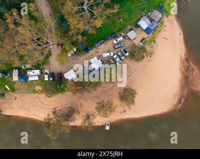 Aus der Vogelperspektive einer Reihe von Wohnwagen und Zelten, die an einem Sandstrand des Murray River in der Nähe von Cobram in Victoria, Australien, campen Stockfoto