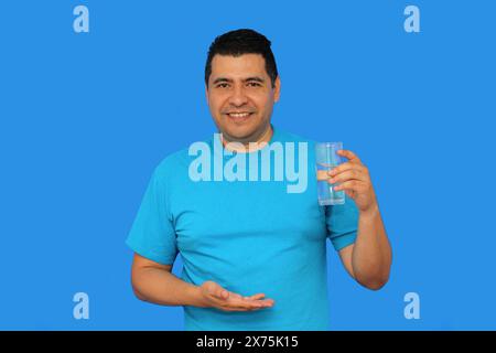 Dunkelhäutiger erwachsener Latino-Mann zeigt sein Glas mit stillem Wasser, um sich bei heißem Wetter mit Feuchtigkeit zu versorgen Stockfoto