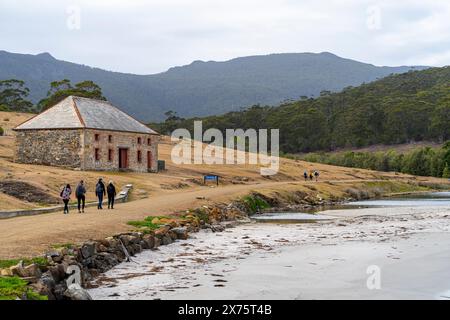 Vier Leute laufen vorbei am Commissariat Store, jetzt an einem Informationszentrum, Maria Island, Tasmanien Stockfoto